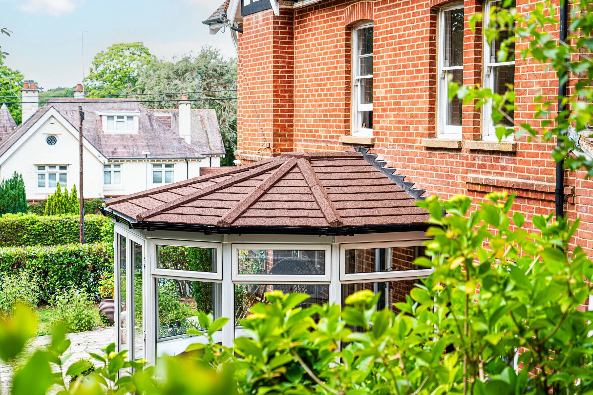 WarmerRoof tiled conservatory roof in terracotta tiles on a bay-fronted conservatory against a red brick house.